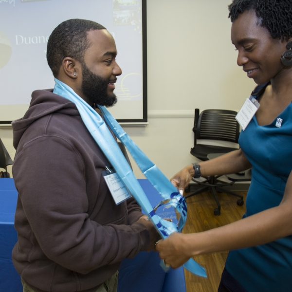 CUNY SPS SEEK (Program Manager) Rianna DeFreece places graduation stole on a SEEK program graduating student. 