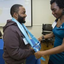 CUNY SPS SEEK (Program Manager) Rianna DeFreece places graduation stole on a SEEK program graduating student. 