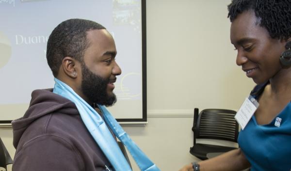 CUNY SPS SEEK (Program Manager) Rianna DeFreece places graduation stole on a SEEK program graduating student. 