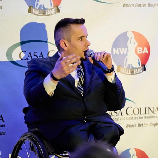 Ryan Martin, CUNY SPS alum and head of CUNY Inclusive and Adaptive Sports, speaking in front of an NWBA Hall of Fame background